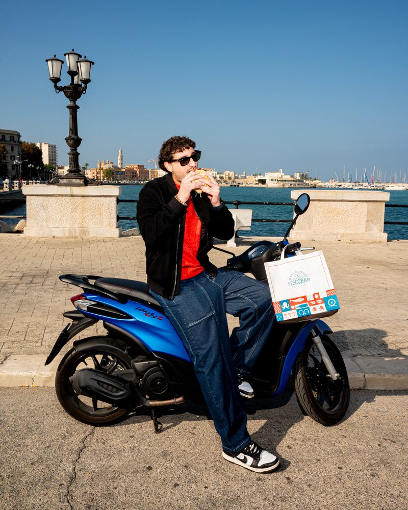 Ragazzo mangia panino al polpo Pescobar sul lungomare di Bari - panini e pokè bowl
